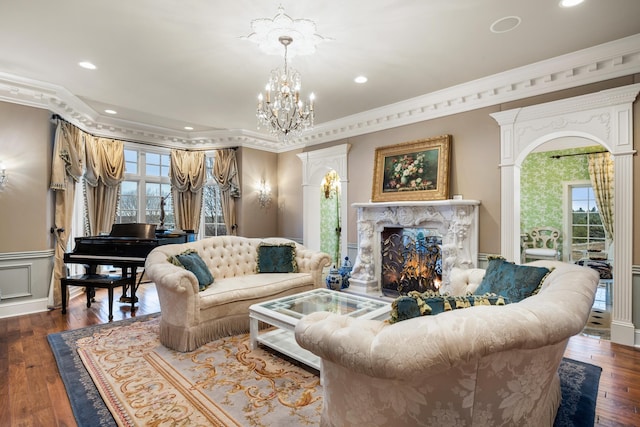 living room with an inviting chandelier, a premium fireplace, wood-type flooring, and ornamental molding