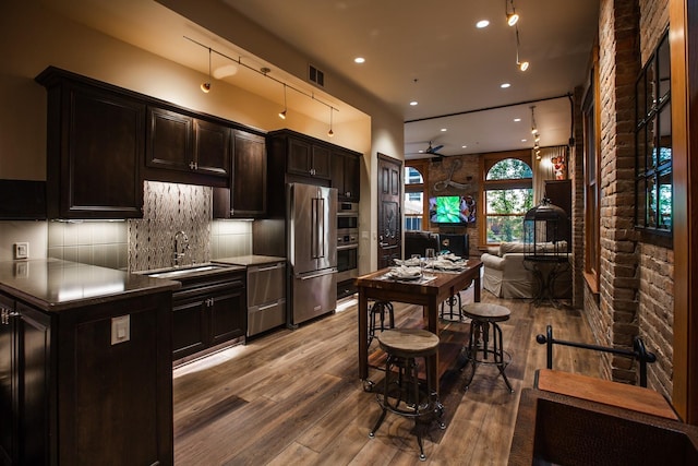 kitchen with sink, decorative backsplash, high end fridge, and hardwood / wood-style floors