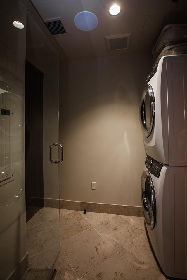 washroom featuring stacked washing maching and dryer and light tile patterned floors