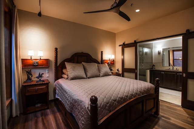 bedroom featuring wood-type flooring, sink, a barn door, and ceiling fan