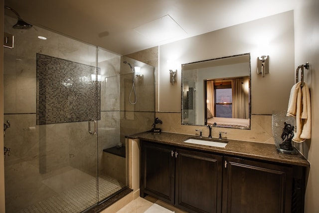 bathroom featuring tile patterned flooring, tasteful backsplash, a shower with shower door, vanity, and tile walls