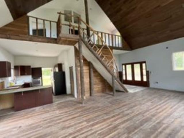 unfurnished living room featuring light hardwood / wood-style floors, french doors, wood ceiling, and high vaulted ceiling