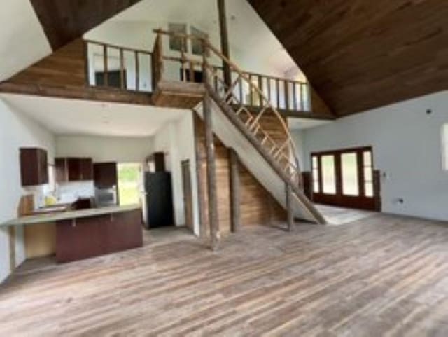 living room with wood ceiling, a high ceiling, french doors, and light hardwood / wood-style flooring