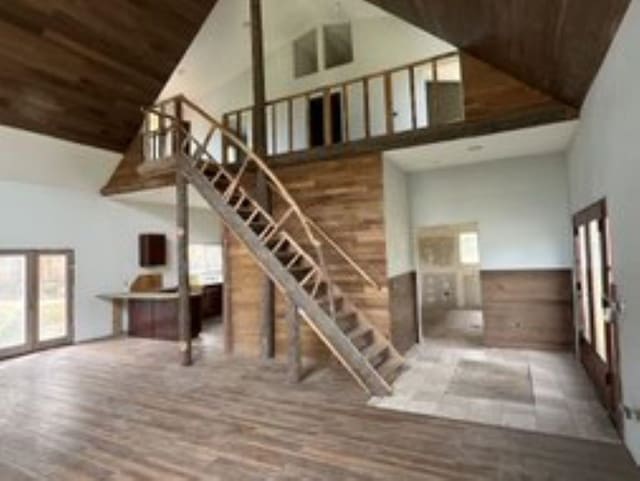 staircase with wooden ceiling, wood-type flooring, and a towering ceiling