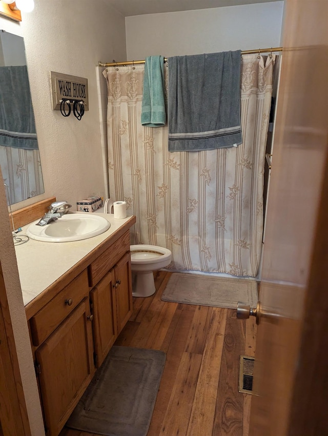 full bathroom with visible vents, a shower with shower curtain, toilet, vanity, and hardwood / wood-style floors