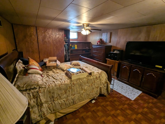 bedroom featuring a ceiling fan and wooden walls