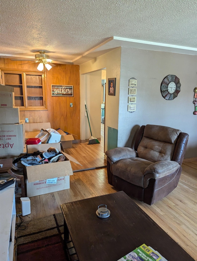 living room with ceiling fan, a textured ceiling, and wood finished floors