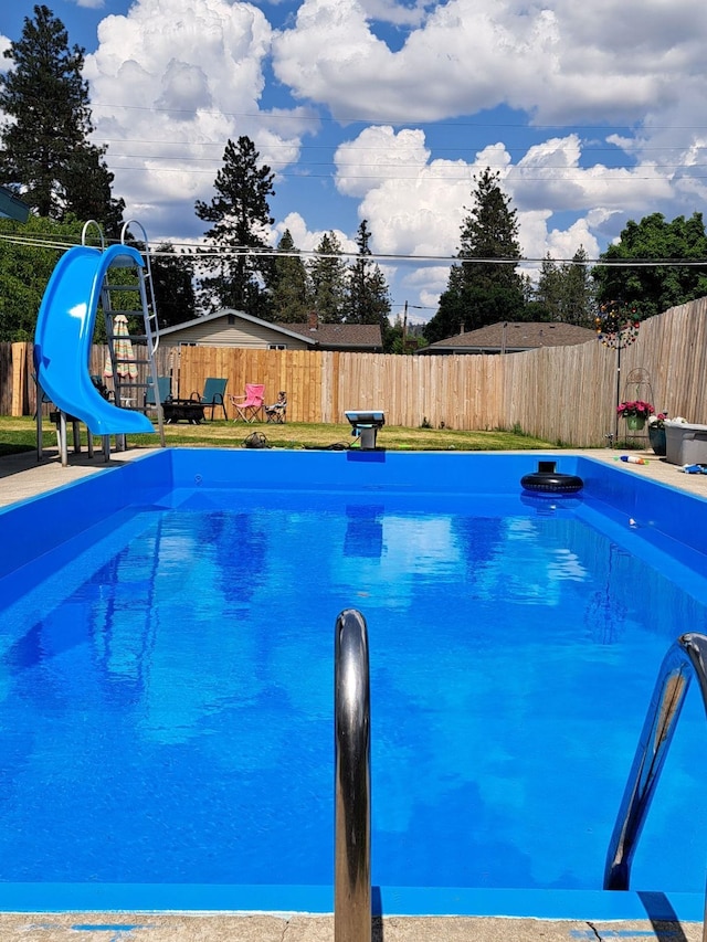 view of swimming pool with a water slide, a fenced backyard, and a fenced in pool