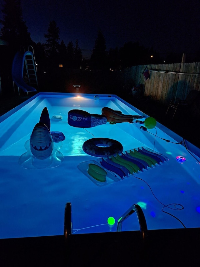 pool at night featuring fence