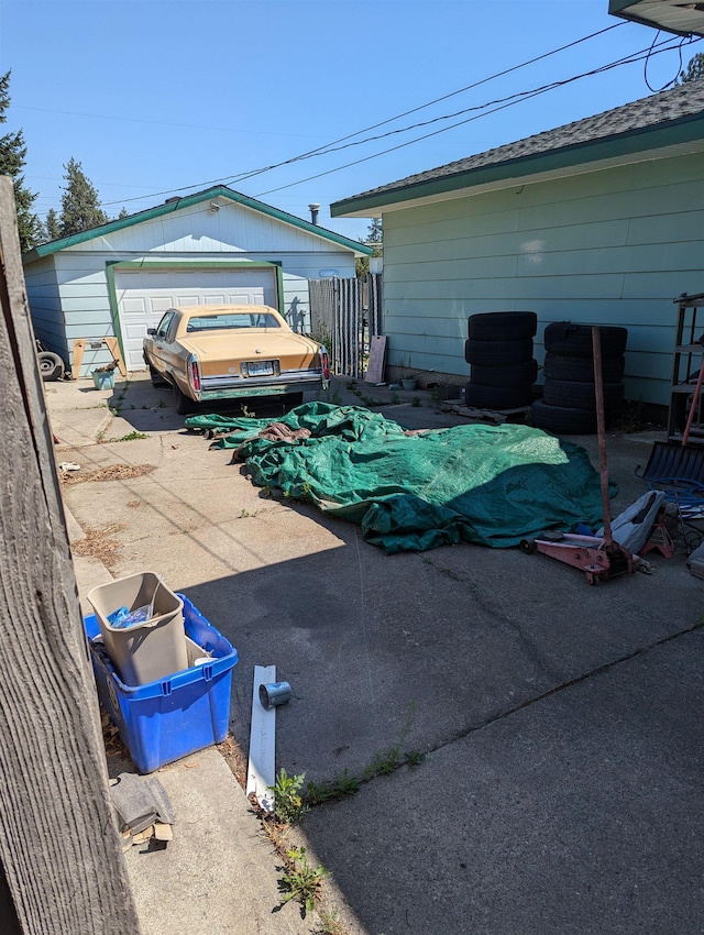 detached garage featuring driveway and fence