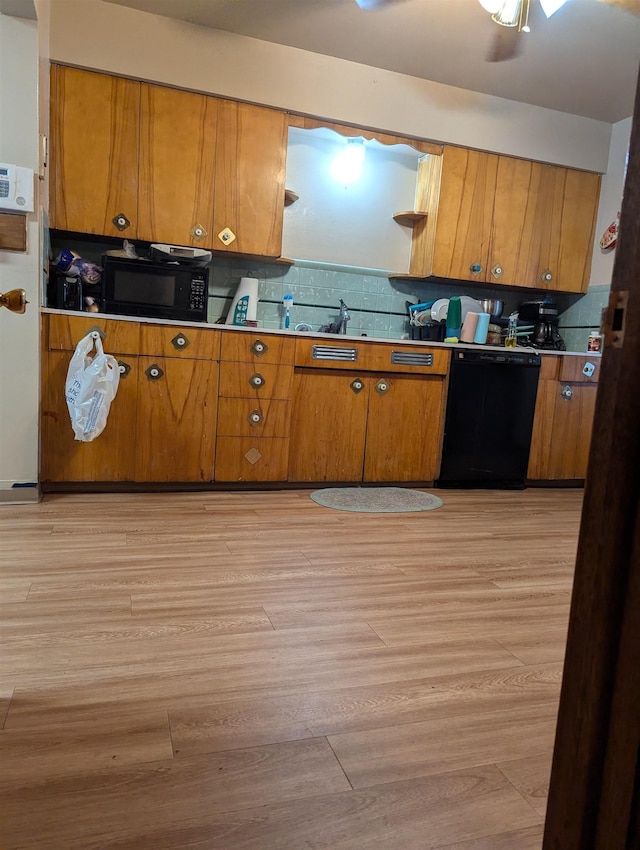 kitchen featuring light wood-style flooring, brown cabinets, backsplash, black appliances, and a sink