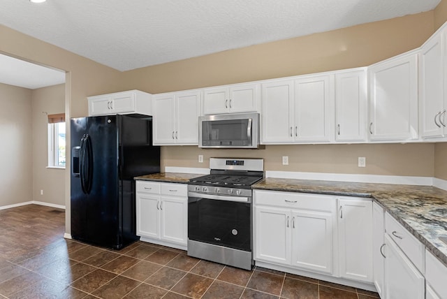 kitchen with dark stone countertops, stainless steel appliances, a textured ceiling, and white cabinets