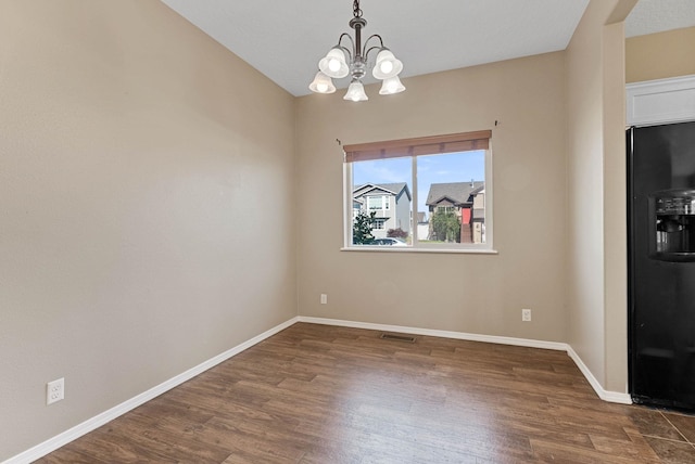 unfurnished dining area featuring dark hardwood / wood-style floors and an inviting chandelier