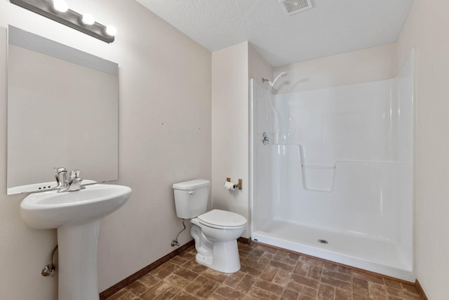 bathroom with toilet, sink, a textured ceiling, and a shower