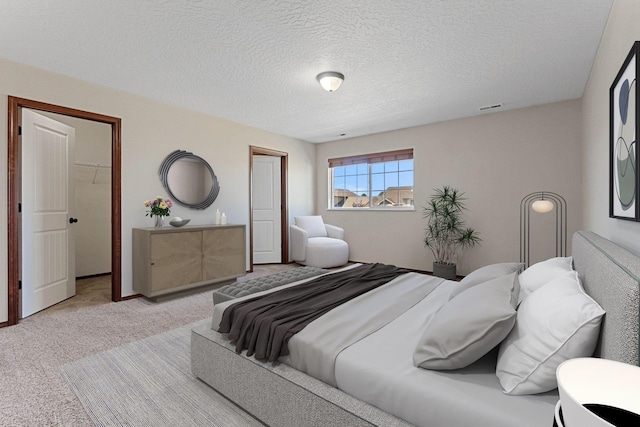 carpeted bedroom with a walk in closet, a textured ceiling, and a closet