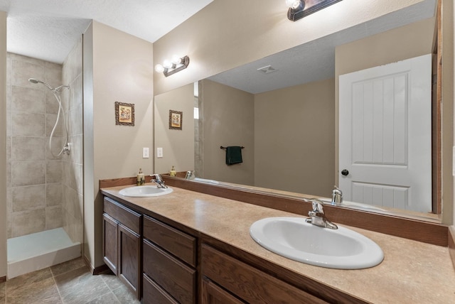 bathroom featuring vanity, tiled shower, and a textured ceiling