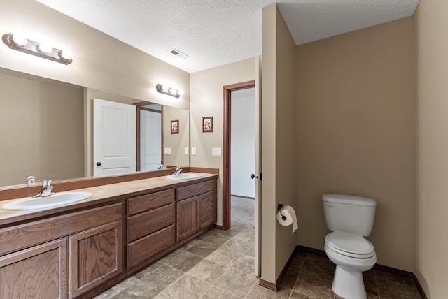 bathroom featuring vanity, toilet, and a textured ceiling