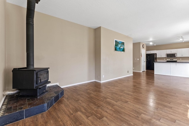 unfurnished living room featuring a wood stove and dark hardwood / wood-style flooring