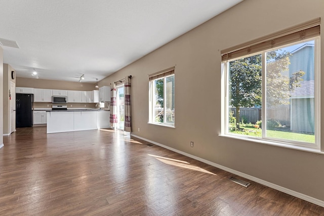 unfurnished living room featuring dark hardwood / wood-style flooring, sink, and a wealth of natural light