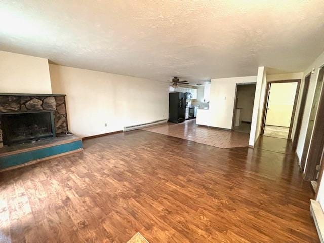 unfurnished living room featuring a stone fireplace, ceiling fan, a baseboard heating unit, and hardwood / wood-style floors