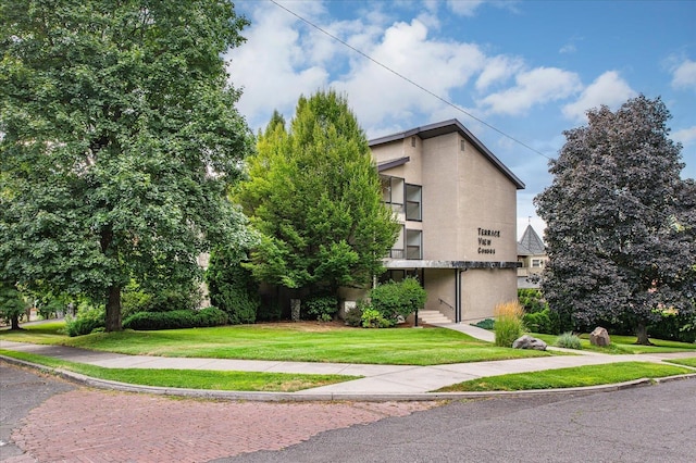 view of property exterior featuring a balcony and a lawn