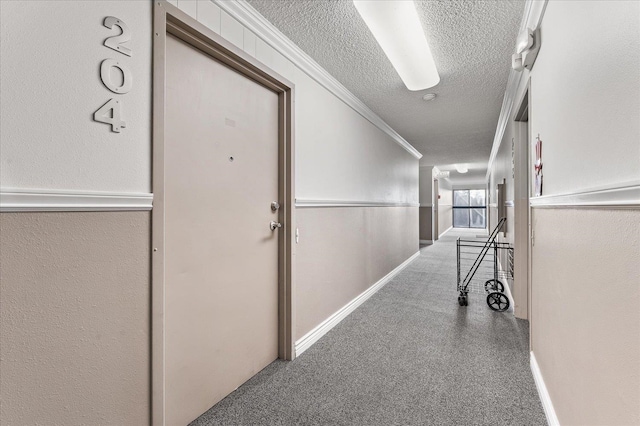 hall with ornamental molding, carpet floors, and a textured ceiling