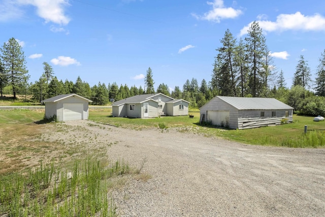 view of yard featuring an outbuilding, a detached garage, and driveway