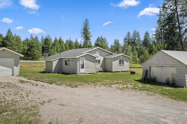 view of front of house featuring a garage, a front lawn, and an outbuilding