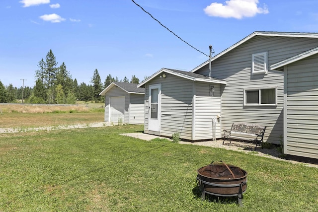 rear view of house with an outbuilding, a yard, a fire pit, and a detached garage