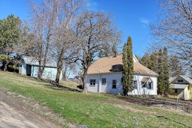 view of home's exterior featuring a lawn and an outdoor structure