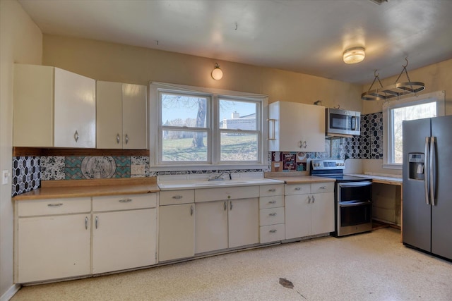 kitchen featuring a sink, stainless steel appliances, light countertops, and white cabinets