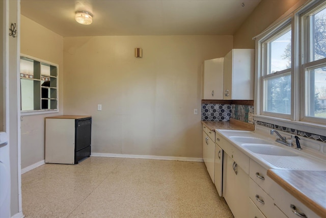 kitchen with a sink, white cabinetry, and baseboards