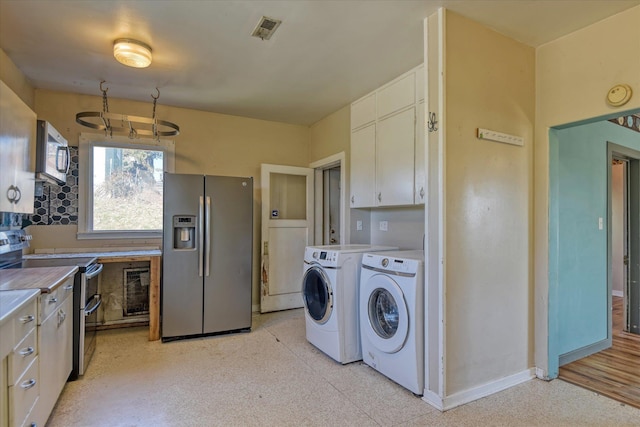 kitchen featuring visible vents, appliances with stainless steel finishes, light countertops, washer and dryer, and white cabinetry