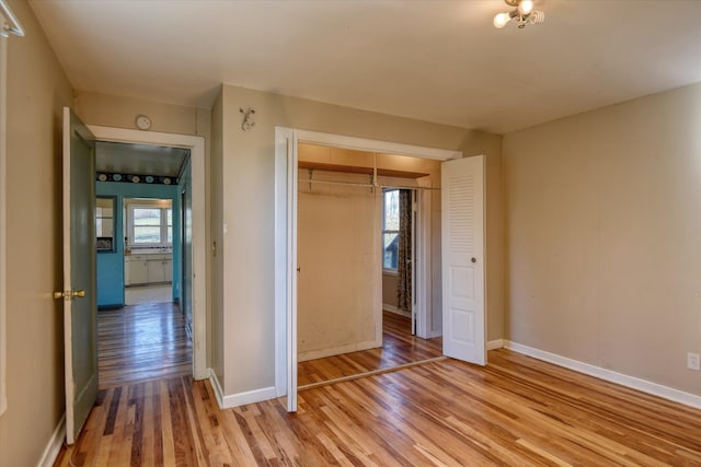 unfurnished bedroom with light wood-style flooring, baseboards, and a closet