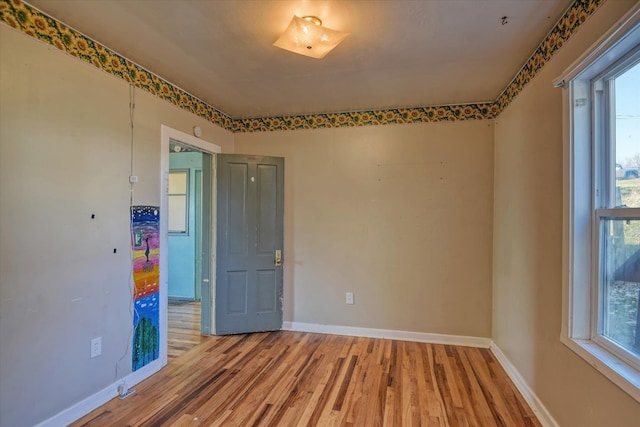 spare room featuring baseboards, plenty of natural light, and light wood finished floors