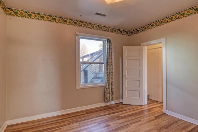 unfurnished room with light wood-style flooring, visible vents, and baseboards