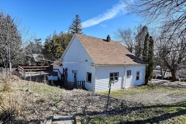 view of home's exterior featuring a shingled roof and a chimney