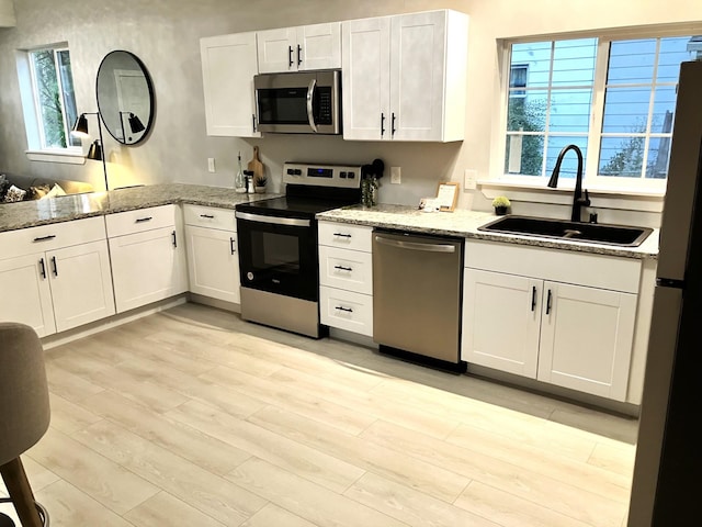 kitchen featuring white cabinetry, sink, stainless steel appliances, and light hardwood / wood-style flooring