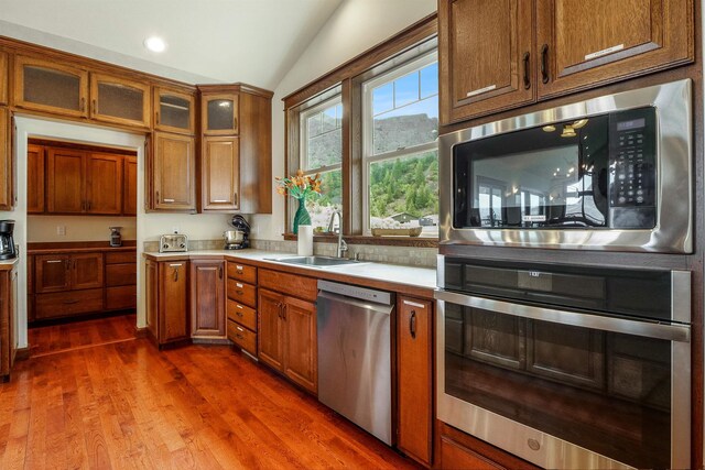 kitchen with dark hardwood / wood-style floors, vaulted ceiling, appliances with stainless steel finishes, and sink