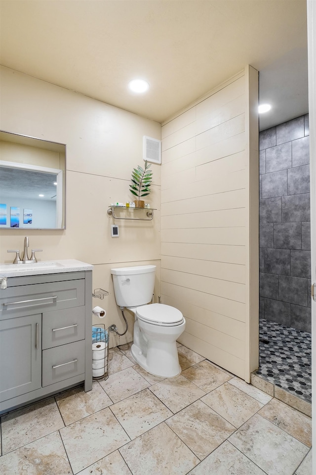 bathroom featuring tile patterned floors, toilet, vanity, and a tile shower