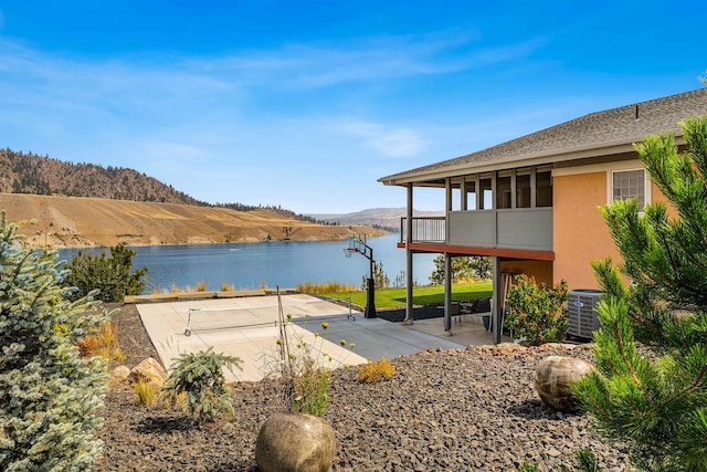 exterior space with a patio area, a water and mountain view, and central AC unit