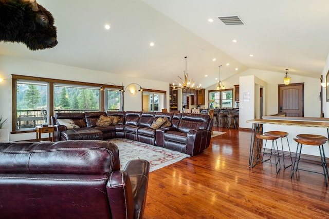 living room with an inviting chandelier, wood-type flooring, and lofted ceiling