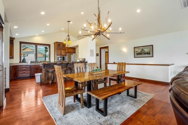 dining area featuring sink, a chandelier, dark hardwood / wood-style flooring, and vaulted ceiling