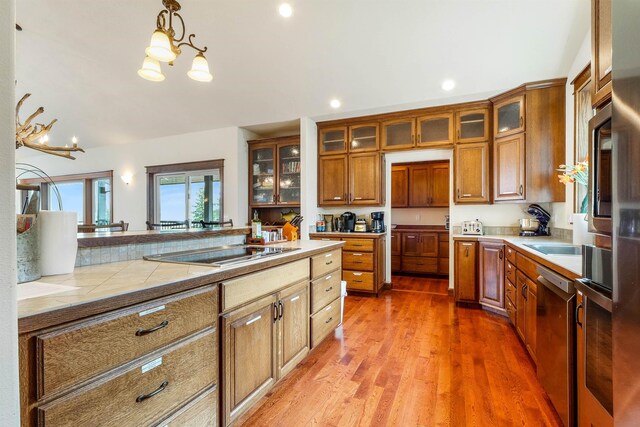 kitchen with black electric stovetop, wood-type flooring, pendant lighting, and a chandelier