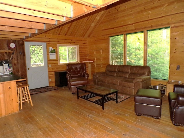 living room with vaulted ceiling with beams, wooden walls, and hardwood / wood-style flooring