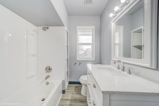 bathroom with visible vents, toilet, wood finished floors,  shower combination, and vanity