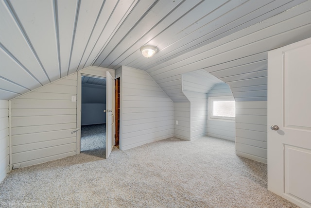 bonus room with lofted ceiling, light colored carpet, and wood walls