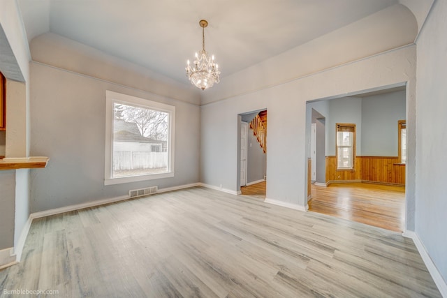 unfurnished dining area featuring a notable chandelier, light wood-type flooring, and a wealth of natural light