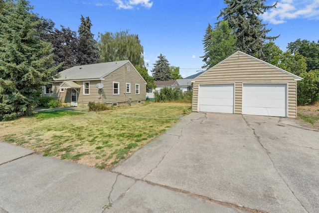 view of front of home with a garage, a front yard, and an outbuilding