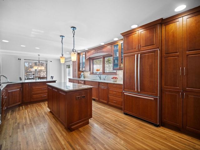 kitchen featuring sink, pendant lighting, a chandelier, a center island, and light wood-type flooring